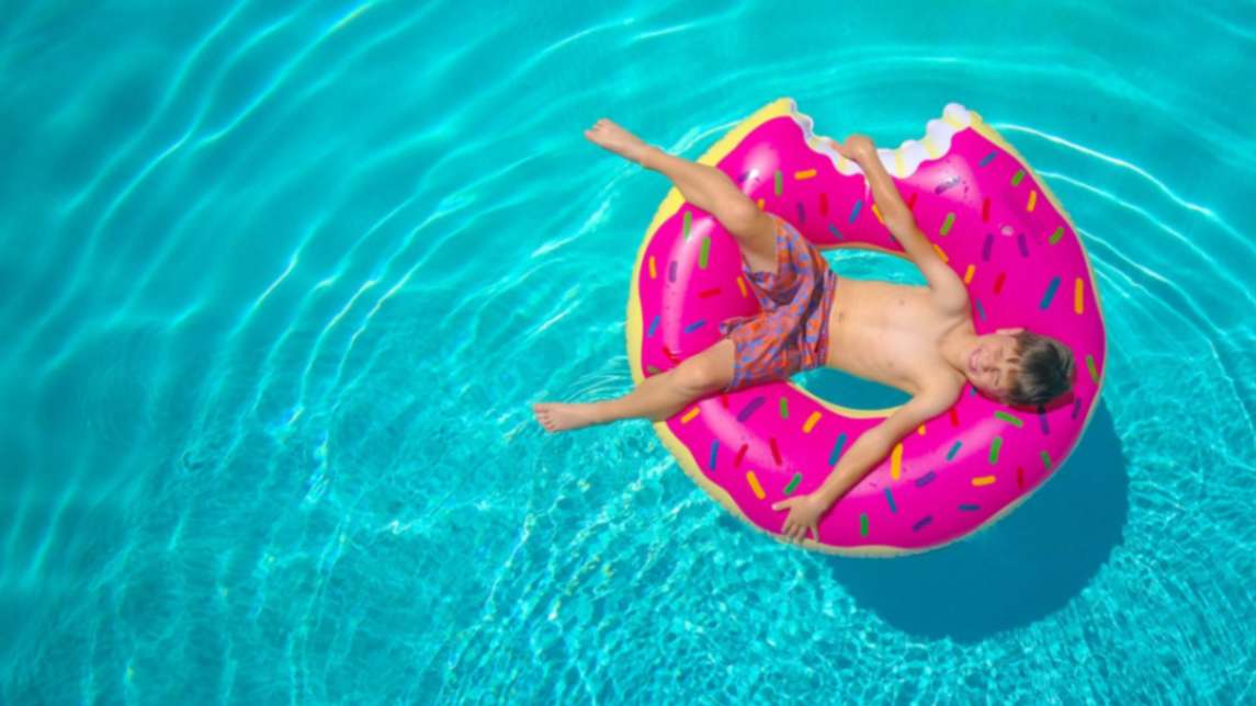 a boy lying on a donut-shaped float ring floating on water