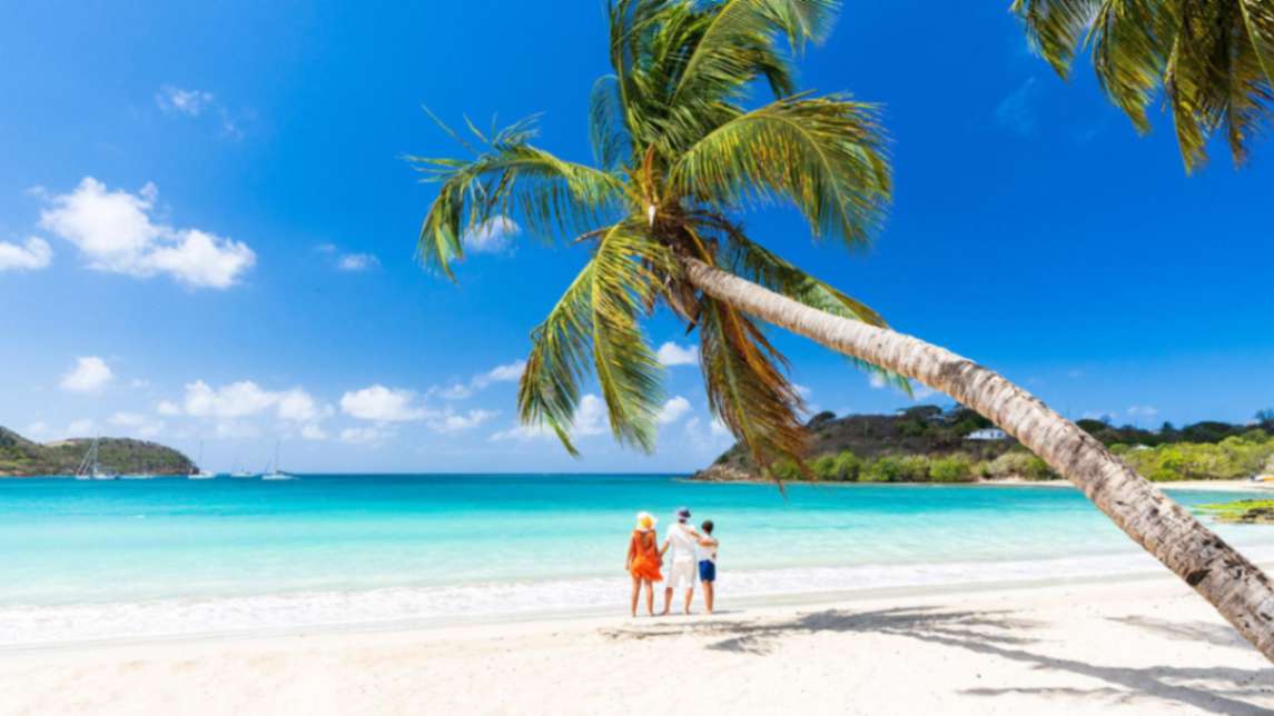 a man, woman, and child standing on a beach staring at the sea