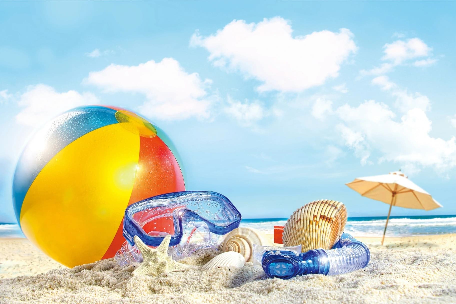 a beach ball, shells, deep diving glasses, snorkell tube, and small umbrella on the beach